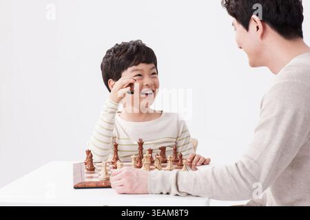 a father and a son playing chess together Stock Photo