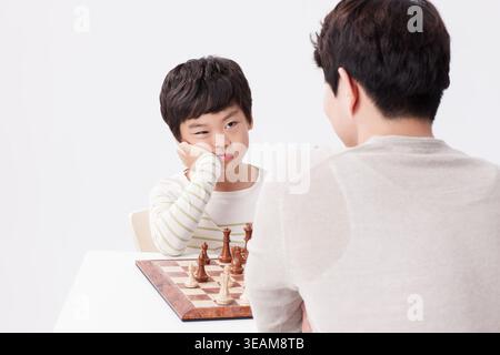 a father and a son playing chess together Stock Photo