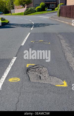 Pontypridd, Rhondda Cynon Taf, Wales - 22 April 2026: Potholes on a main road through a residential area marked out with yellow paint for repair. Stock Photo