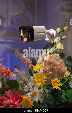 Security camera hidden among lush flowers. Conceptual image of surveillance, privacy, social monitoring, and hidden observation in modern world Stock Photo