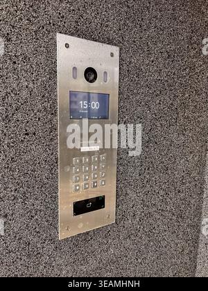 Close up of modern intercom panel with camera and numeric keypad on exterior wall. Focus on access control, security systems, and smart building techn Stock Photo