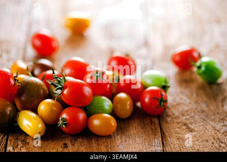 a pile of different color mini tomatoes on a wooden table Stock Photo