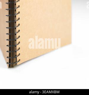 A close-up shot of a blank, brown spiral-bound book, lying open on a white surface. Stock Photo