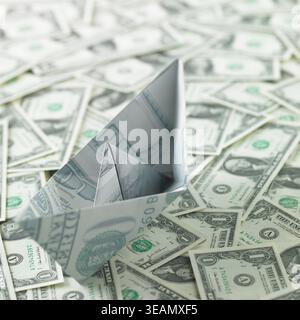A paper boat made from a $100 bill is seen among a sea of US currency. Stock Photo