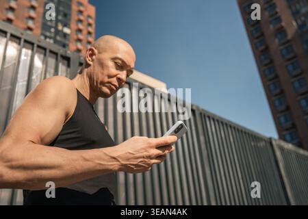 Athletic man using smartphone outdoors urban lifestyle concept Stock Photo