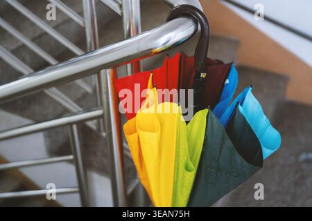 Colorful umbrella hanging on stainless steel railing, vibrant rainbow canopy draped over modern Stock Photo
