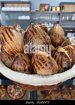 Freshly baked crispy bread rolls in a basket displayed on a bakery counter background. Mobile photo Stock Photo