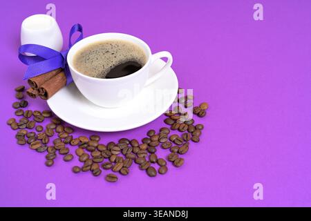 Cup of Black Coffee with Cinnamon Sticks and Coffee Beans on a Purple Background Stock Photo