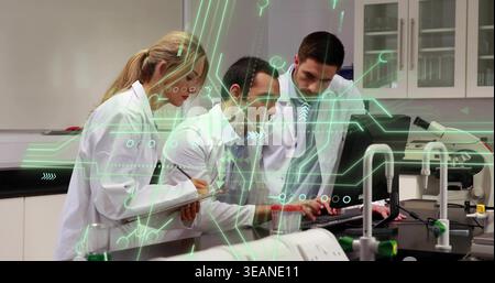 Typing three researchers in lab coats, center wearing tie, at lab bench with monitor and clipboard. Laboratory, collaboration, teamwork, data, analysi Stock Photo