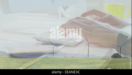 Typing adult hands resting on small keyboard at pale desk, merging with wind turbines, mug, watch. Keys, office, sustainable, energy, landscape, duali Stock Photo