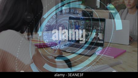 Writing teen girl wearing striped sweater taking notes at study table, laptop hologram, copy space. Group, notebook, desk, overlay, grid, learning, ed Stock Photo