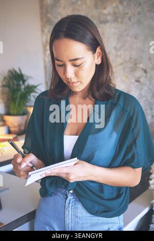 Creative, woman and writing in notebook in home for planning, story reminder and remote work. Freelancer, diary and notes for copywriting agenda Stock Photo