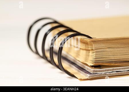 Macro shot of a black spiral binder on a kraft paper notebook over a light surface Stock Photo