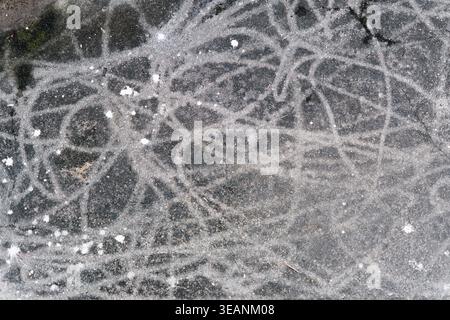 Overhead flat lay of weathered gray concrete floor covered in chaotic white scratch lines and paint marks, creating an abstract textural pattern. Stock Photo