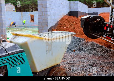 Workers use wheelbarrow bucket to prepare foundation of building at construction site Stock Photo