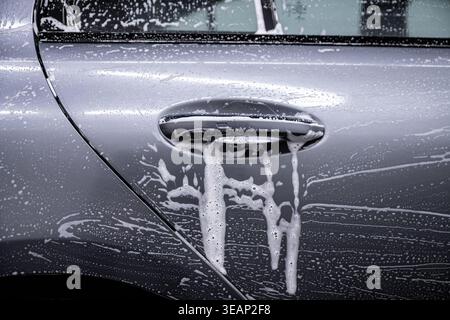 Water beading and runoff on protected car paint surface with door handle close up Stock Photo
