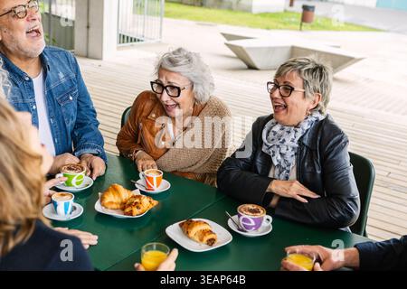 Senior friends enjoying breakfast together laughing at a cafe Stock Photo