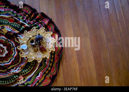 Top view of a tea ceremony set on a carved wooden tray over a bright woven rug and warm plank floor. Mindful tea rituals and slow living create calm Stock Photo