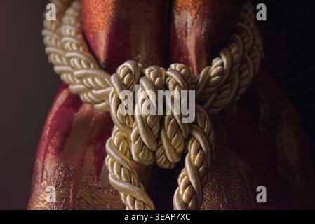 Coarse rope knots tightly around a richly textured surface. Warm tones suggest heritage or craftsmanship Dark background emphasizes detail and texture Stock Photo
