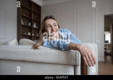 Emotional wellness of happy mature woman relaxing at couch carefree smiling enjoy time alone at home Stock Photo