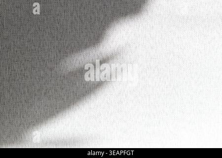 A textured white fabric, linen or a similar woven material, with a soft grey shadow cast across the upper left portion Stock Photo