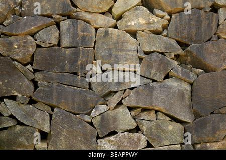 rough natural stone wall with irregular gray rocks background, dry stacked masonry surface texture, full frame architectural concept Stock Photo