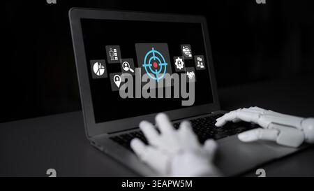 A robotic hand interacts with a digital laptop interface showcasing a targeting symbol and various graphical icons, illustrating advanced technology Stock Photo