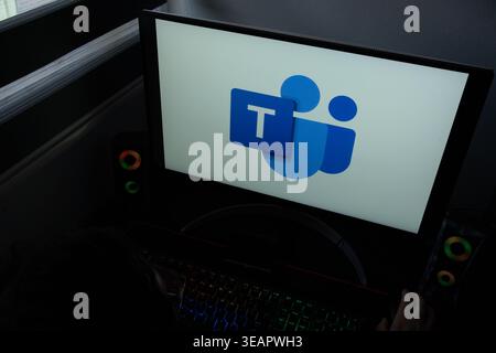 The Microsoft Teams communication platform logo is displayed on a computer monitor in a dark home office setting Stock Photo