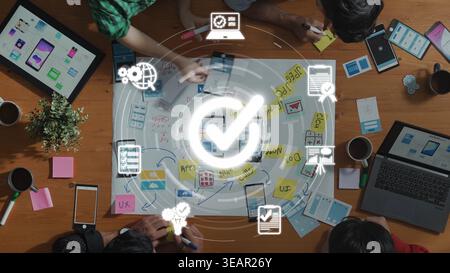 A dynamic workspace showcases a team engaged in collaborative planning, using digital devices and visual aids to develop user experience strategies Stock Photo