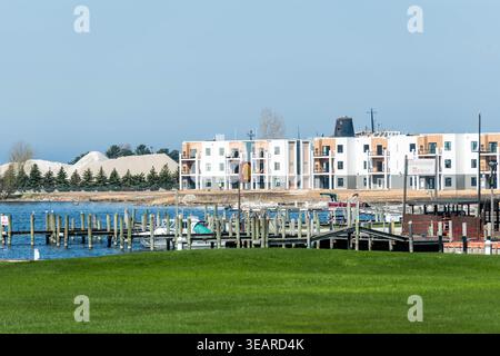 LUDINGTON, MICHIGAN, USA - 23 April 2026. The newly constructed Lake District Flats apartment complex is seen across Pere Marquette Lake from the Ludington city marina, with the smokestack of the retired Ann Arbor Railroad carferry SS Spartan visible behind the building and industrial sand piles in the background, illustrating the dramatic transformation of Ludington's waterfront from industrial to residential. Credit: Jeffrey Wickett/Ģ����ý Live News. Stock Photo
