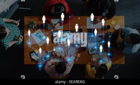This image captures a diverse group of professionals collaborating at a wooden table, showcasing digital tools and global communication symbols in an Stock Photo