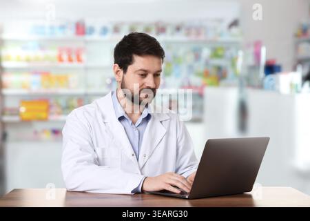 Pharmacist using laptop at table in drugstore Stock Photo