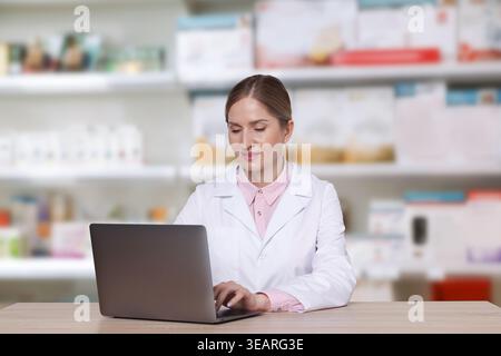 Pharmacist using laptop at table in drugstore Stock Photo