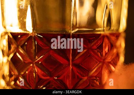 A textured glass filled with amber whiskey under warm lighting that highlights the reflections. Concepts: an elegant atmosphere associated with luxury Stock Photo