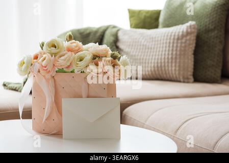 Delicate lifestyle composition featuring a quilted pink gift bag filled with cream and blush ranunculus flowers, accented by ribbon handles and decora Stock Photo