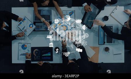 A diverse group of professionals collaboratively analyzing data in a modern office setting, surrounded by digital graphs and technology. The teamwork Stock Photo