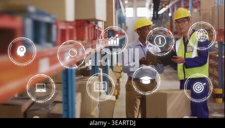 Consulting workers wearing hard hats, vest checking tablet by pallet boxes in racking, with icons. Warehouse, logistics, inventory, collaboration, tea Stock Photo