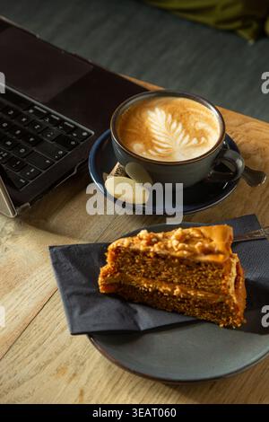 A laptop on a table with a coffee and a slice of walnut cake Stock Photo