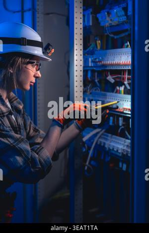Electrician testing electrical panel with voltage tester. Industrial maintenance. Stock Photo