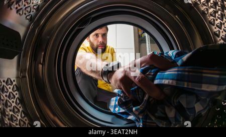 Man loading clothes into washing machine Stock Photo