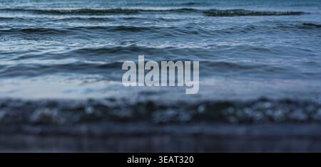 Dark sea waves under evening sky. Water texture on the coast at dusk. Stock Photo