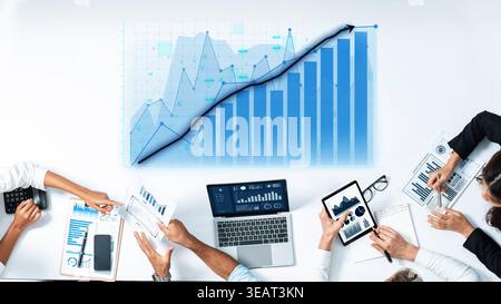A diverse business team collaboratively engages in analyzing financial data, using technology and visual graphs within a modern office environment Stock Photo