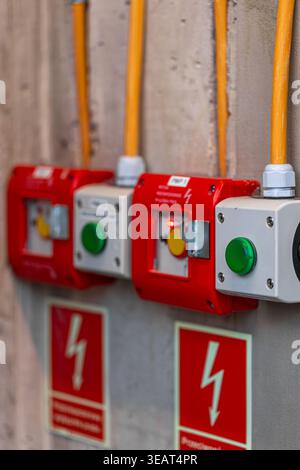 Industrial emergency stop buttons on a wall. Safety equipment with electrical cables. Stock Photo