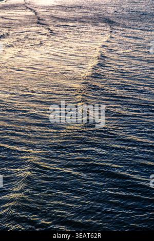 Boat wake on sea water surface. Wave texture in evening sun rays. Stock Photo