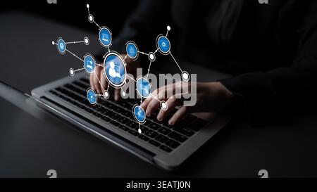 A business professional actively engaging with a laptop, surrounded by digital icons representing connections in technology and communication Stock Photo