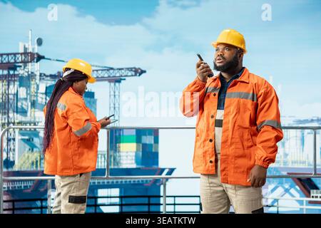 Offshore platform employee using two way radio communication solution to coordinate workflow in oil and gas operations. Worker using walkie talkie enabling quick responses during emergency procedures Stock Photo