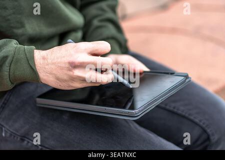 Person using a stylus on tablet screen Stock Photo