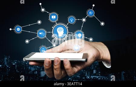 A hand holding a smartphone displays an array of floating digital icons, symbolizing the intersection of technology and innovation against a dark Stock Photo