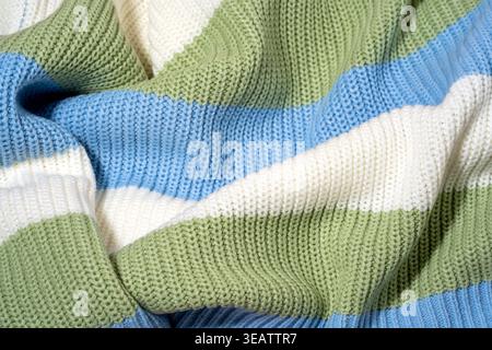 Close-up of green, blue and white color striped knitted sweater texture with soft folds filling frame. Concept of tactile textile detail, material sur Stock Photo