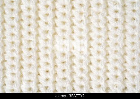 Close-up sweater texture in white ivory color, macro knitted surface and synthetic fiber detail. Concept of tactile textile material, practical easy-c Stock Photo
